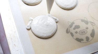 Piping cow macaron design with macaron batter on silicone mat