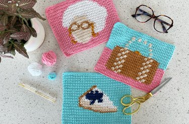 Trio of trivets inspired by "Golden Girls," featuring a cheesecake slice, the silhouette of an elderly woman's head and a brown purse on a pink and blue background