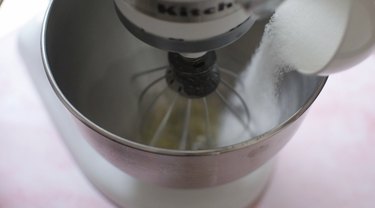 Egg whites and sugar being mixed in a KitchenAid mixer