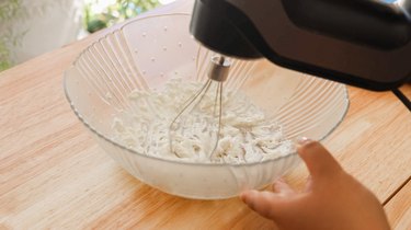 Whipping cream cheese in a glass bowl.