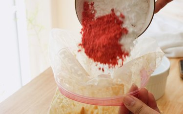 Pouring strawberry powder and powdered sugar into bag.