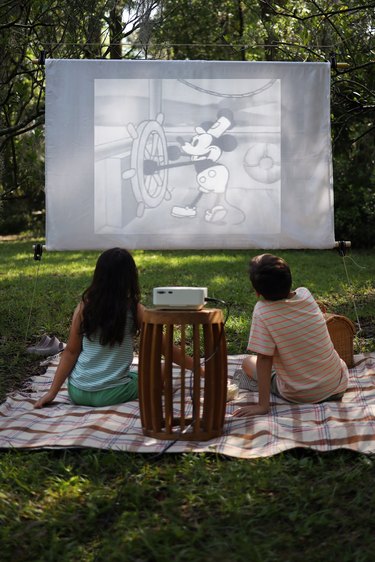 Two kids watching a movie on an outdoor screen