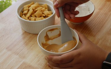 Mixing white chocolate and cookie butter in a bowl.