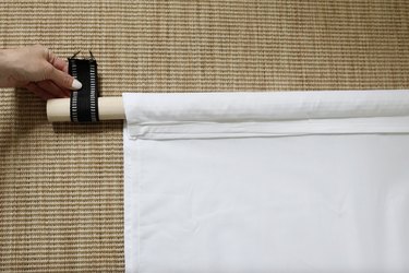 Folding strip of nylon webbing around dowel to mark grommet placement