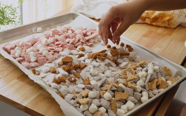 Topping muddy buddies with Biscoff cookies.