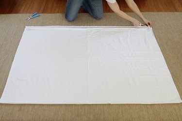 Running a strip of hem tape along edge of sheet