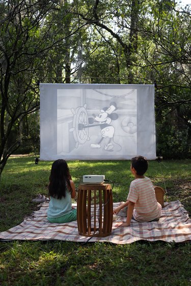 Two kids watching a movie on an outdoor screen