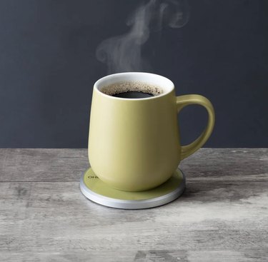 Chartreuse mug with a rounded handle sitting on a matching, wireless warming pad.