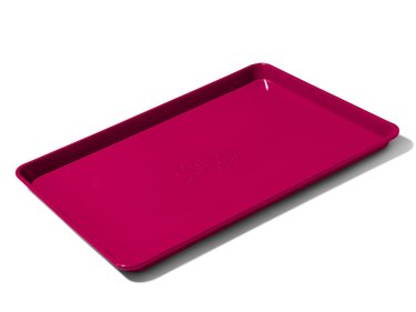 Great Jones Holy Sheet half sheet pan shown in red ("raspberry") on a white ground