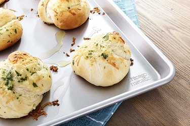 Chicago Metallic sheet pan, shown with baked cheese buns on a wooden surface
