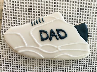 White and navy blue sneaker cookie details with the word "dad" added with navy blue royal icing