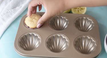 Adding baked madeleine to melted chocolate.