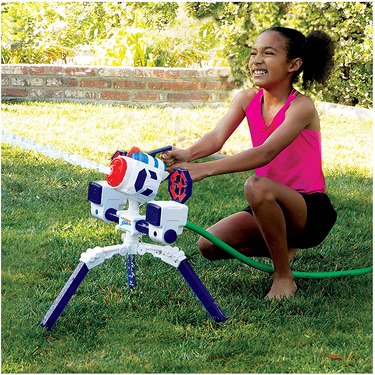 Girl playing with WowWee Nerf Super Soaker RoboBlaster in grassy backyard.