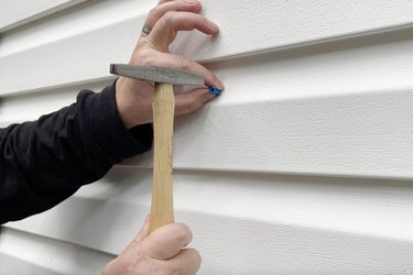 Hammering a plastic anchor into exterior siding