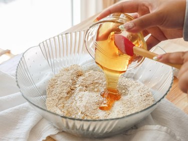 Pouring honey into mixing bowl.