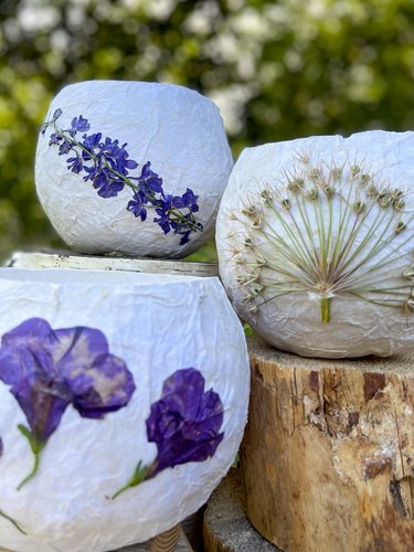 Three finished pressed-flower paper lanterns with whimsical flowers and blooms