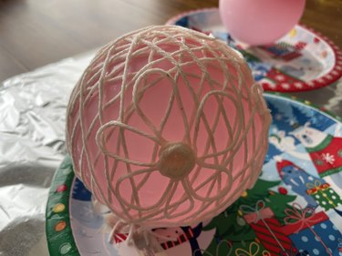 A pink balloon with strings around it.