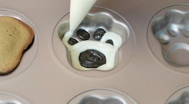 Piping chocolate into paw print madeleine pan