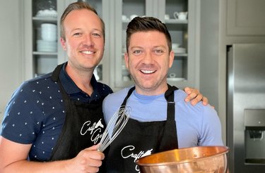 The Craft Grooms in matching aprons, holding cooking tools and dreaming up their next baking project!