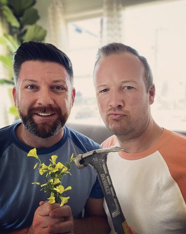 DIY experts Tim and Brad holding flowers and a hammer. Why flowers? They're mourning a recent craft fail!