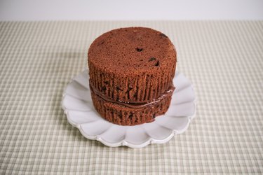A chocolate muffin with the top cut off placed on top of another topless chocolate muffin