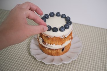 A blueberry muffin cake topped with a ring of fresh blueberries