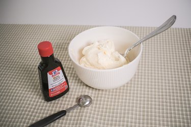 A bowl of vanilla frosting and a bottle of lemon extract