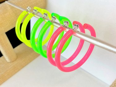 Three pairs of hoop earrings in neon yellow, green and pink