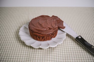 A chocolate muffin, top removed, with chocolate frosting spread on top