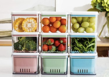 Nine pink, green and blue food containers with fruits and veggies