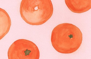 A closeup of watercolor mandarin oranges against a pink background