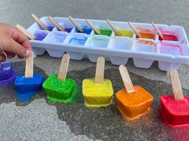 closeup of ice chalk with little hand picking up blue piece