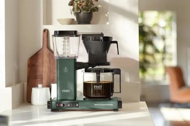 Moccamaster KBGV Select Coffee Brewer in color juniper sitting on a white countertop with coffee in the carafe.