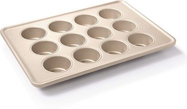 OXO nonstick muffin pan in bronze-colored aluminized steel, depicted in 3/4 view on a white ground