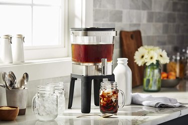 KitchenAid Cold Brew Coffee Maker perched on a black four-legged stand that allows you to easily dispense cold brew coffee into your mug from the tap.