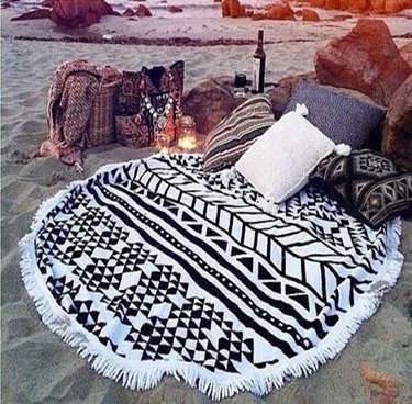 Cckiise Round Mandala Beach Throw on the beach surrounded by pillows and picnic essentials.