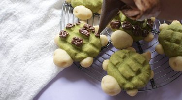 Decorating turtle cookies with chocolate.