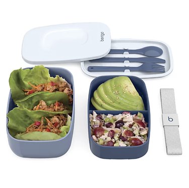 Two blue bento boxes full of food with the lids off, utensils attached to lid.