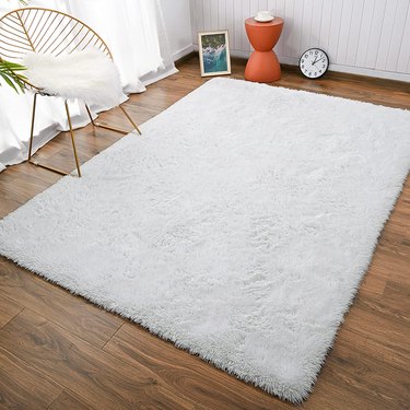 White shag rug on the floor in front of a chair