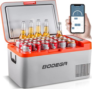 Gray and red cooler filled with cans and bottles of beer, next to a hand holding a smart phone showing an app.