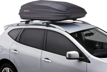 Large black cargo box on top of a silver SUV against a white background.