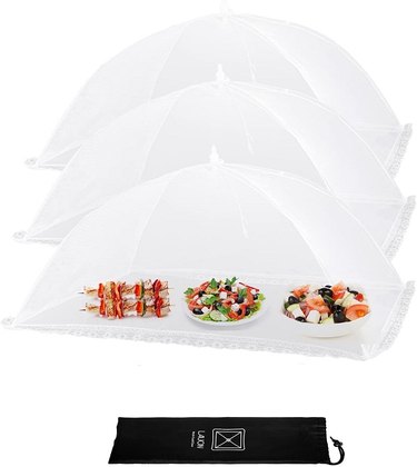 Three extra-wide, large white mesh food covers, one protecting salads and kebobs.