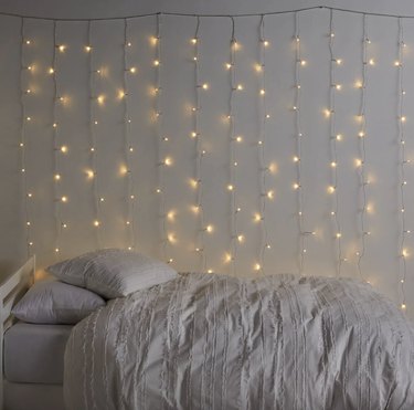 String lights hanging over twin size bed with white bedding