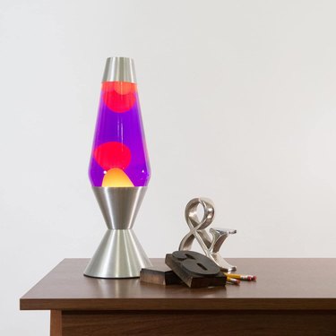 Silver, purple, pink lava lamp on a table next to desk items