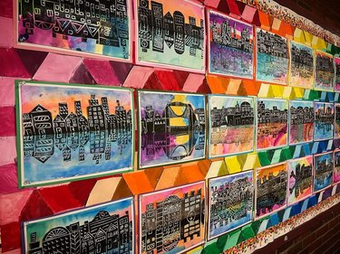 Wall of rainbow-colored stripes and a series of colorful cityscape prints