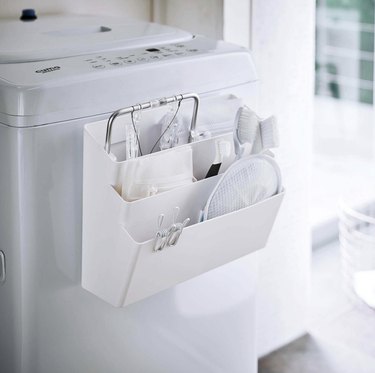 White magnetic caddy attached to a washing machine with three storage compartments.