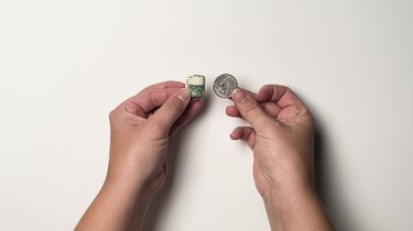 A one-dollar bill folded as small as possible next to a quarter