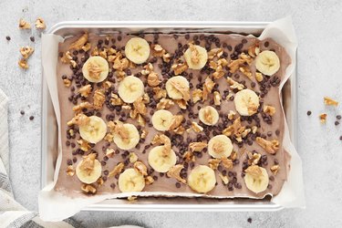 Chocolate yogurt topped with bananas, walnuts, cashew butter and mini chocolate chips