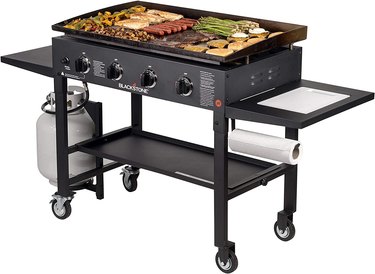 Blackstone flat-top grill shown on a white ground, with the cooking surface filled with an array of foods