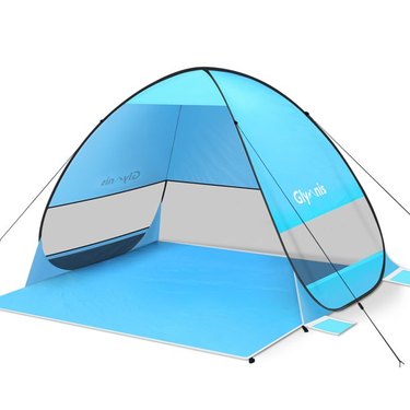 Blue beach tent enclosed on three sides with a large base for laying out.